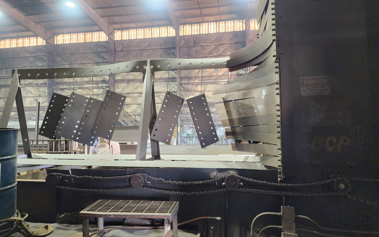 Blasted connection plates hanging on the line at a Regal Industrial wheelblast machine