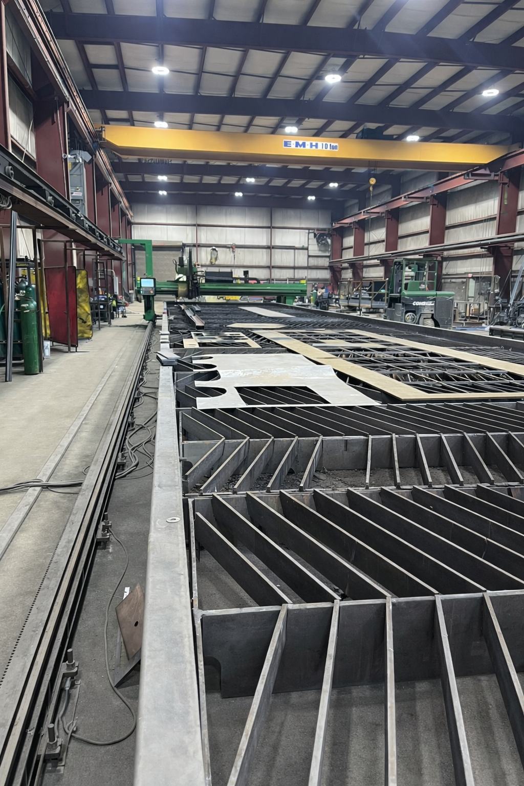 Large fabricated steel assembly and CNC cutting table on the shop floor at Regal Industrial, with a 10-ton overhead crane above
