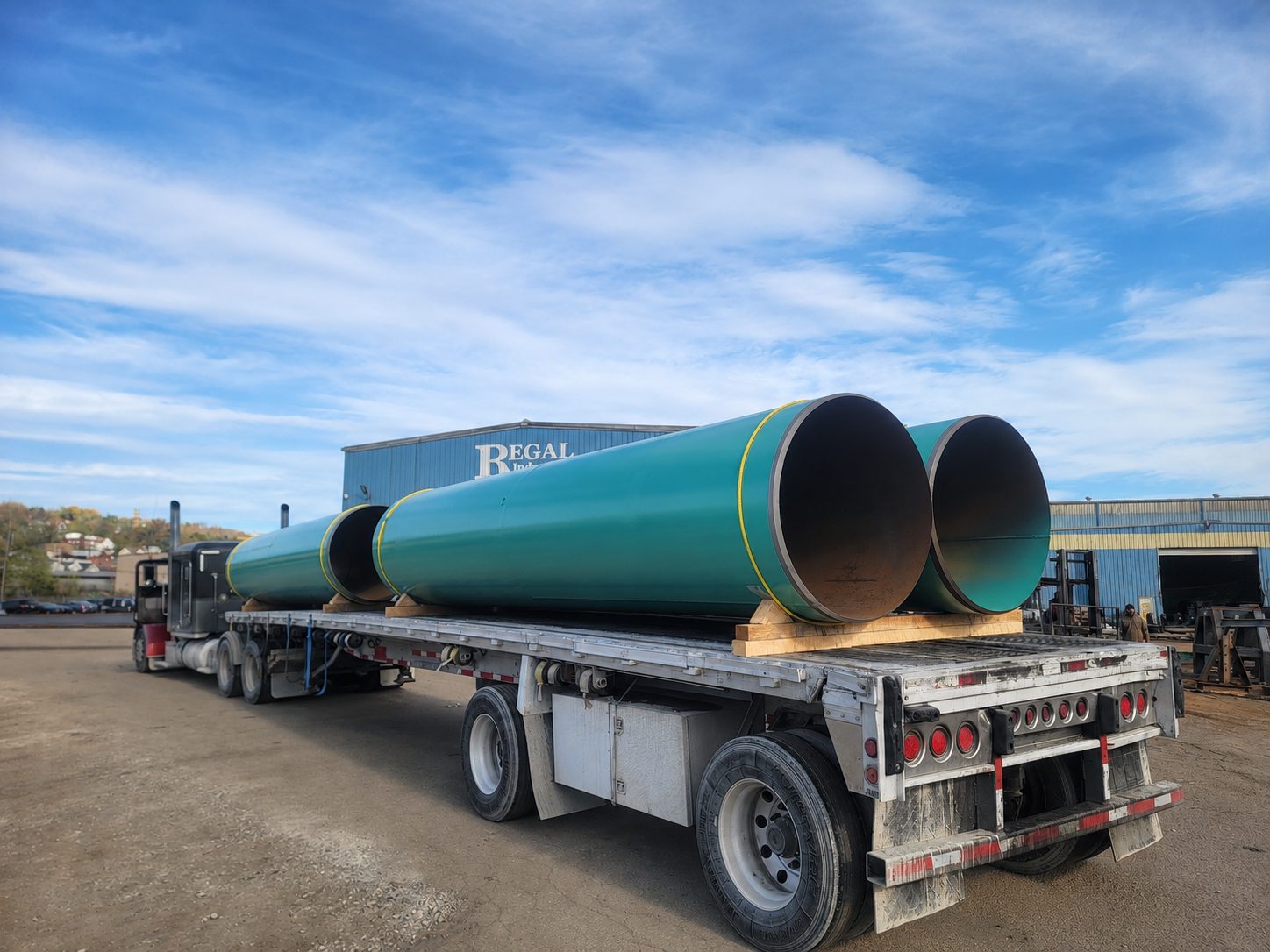 Two large coated steel pipes secured on a flatbed trailer outside the Regal Industrial facility in Donora, Pennsylvania